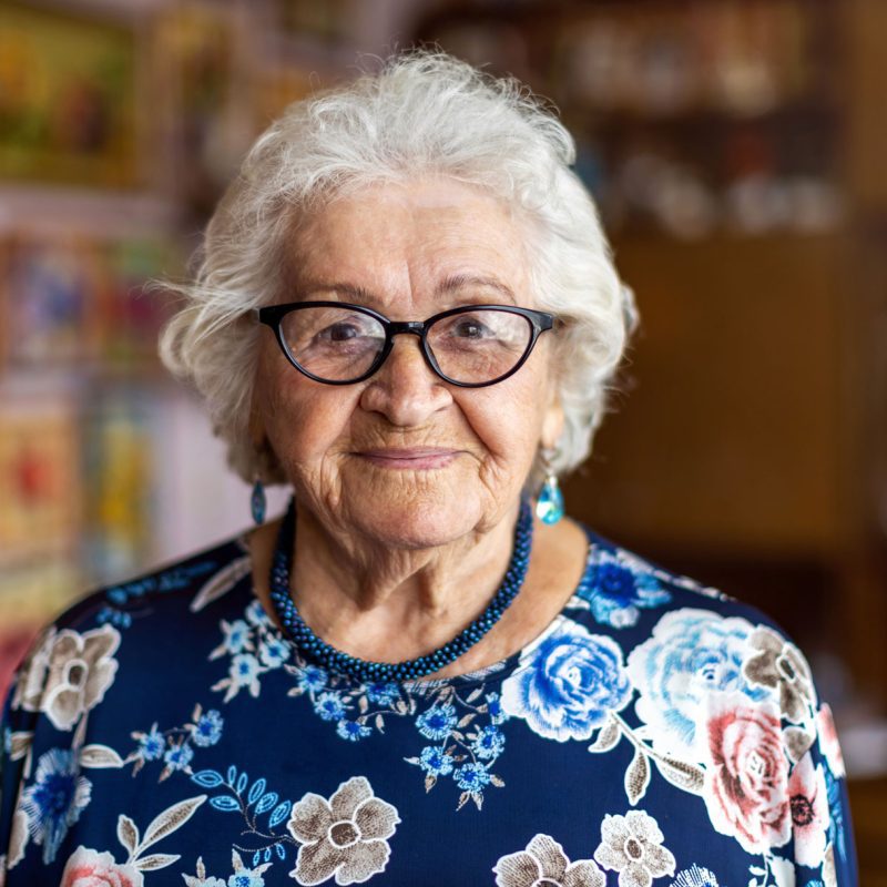 A portrait of an older woman wearing glasses and a navy floral shirt